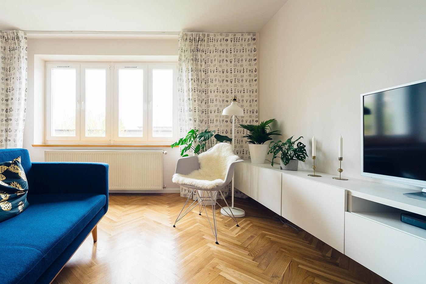 Bright living room with herringbone floor and a blue sofa